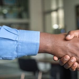 Close-up of two men's handshake symbolizing agreement in an office.